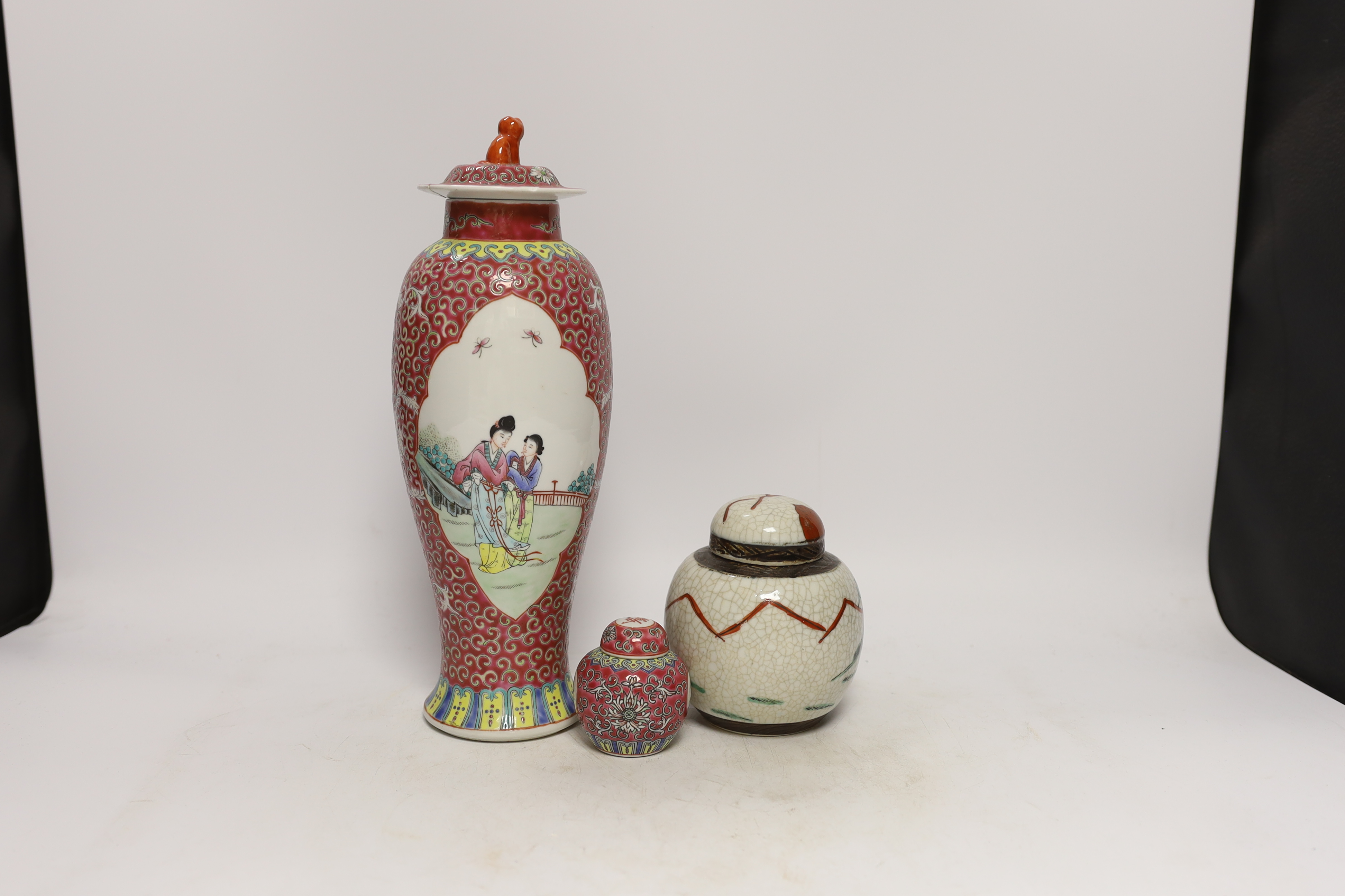 An early 20th century Chinese famille rose vase and cover, similar small jar and cover and a famille verte crackleglaze jar and cover, tallest 31cm